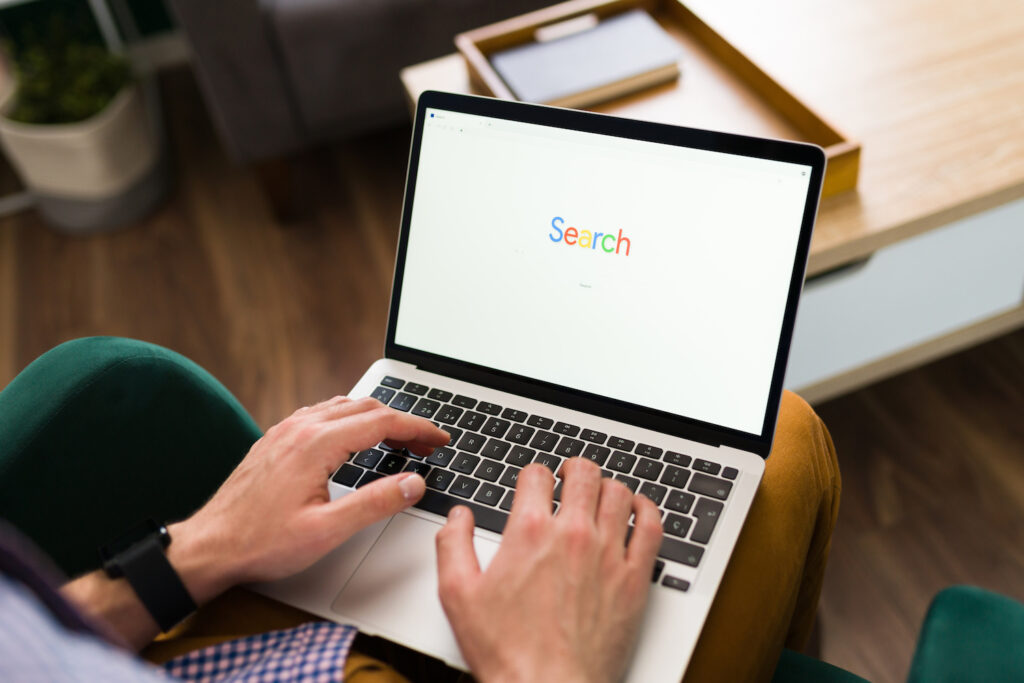 Adult person typing a word search on a website bar on his laptop. Man going online with a search engine